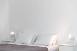 a white bedroom with white walls and a bed with white pillows at Mary & Jo's Studios in Naxos Chora