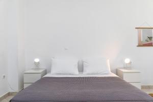 a bedroom with white walls and a bed with two night stands at Mary & Jo's Studios in Naxos Chora