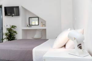 a white bedroom with a bed with a tv on the wall at Mary & Jo's Studios in Naxos Chora