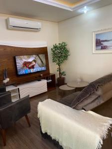 a living room with a couch and a flat screen tv at Casa Petri Gramado casa inteira para 7 pessoas ideal para famílias in Gramado