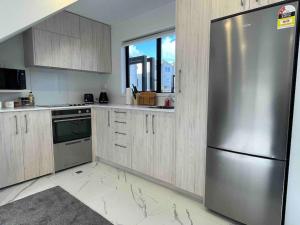 a kitchen with a stainless steel refrigerator and a window at Coastal Sanctuary in Christchurch