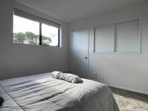 a bedroom with a large bed with two windows at Coastal Sanctuary in Christchurch