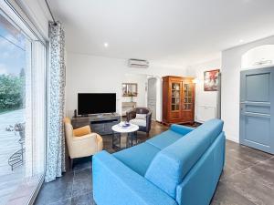 a living room with a blue couch and a tv at Terrasse, Piscine privée & Charme provençal in Tourrettes-sur-Loup