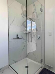a shower with a glass door in a bathroom at Coastal Sanctuary in Christchurch
