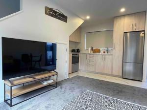 a living room with a large television and a kitchen at Coastal Sanctuary in Christchurch