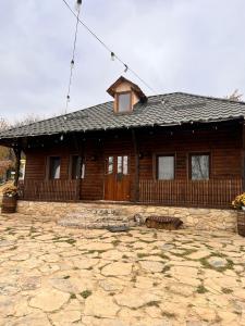 a log house with a stone patio in front of it at Crâșma Trei Fântâni - Cebotaru in Hogineşti