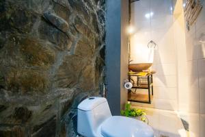 a bathroom with a stone wall and a white toilet at Casa playa Puerto Luz, Alquiler vacacional in Santa Marta +10 photos