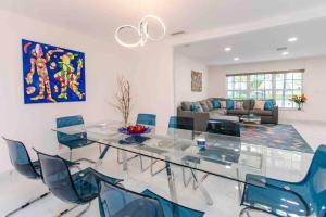 a dining room with a glass table and blue chairs at MIAMI Art Villa Heated Saltwater Pool with SPA EV in Dania Beach