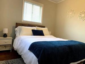 a bedroom with a bed with a blue blanket and a window at Rose District Willow House By Tulsa Getaways in Broken Arrow