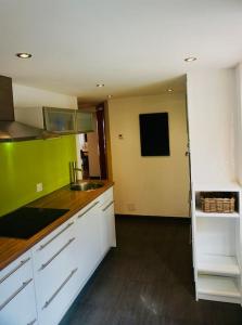 una cocina con armarios blancos y paredes verdes en Central Local Flat, en Zermatt