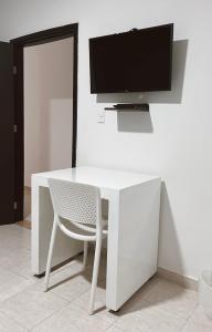 escritorio blanco con silla y TV en la pared en Casa de huéspedes SKY BLUE, en Barranquilla