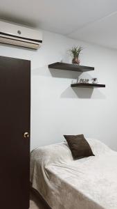 Un dormitorio con una cama y dos estantes en la pared. en Casa de huéspedes SKY BLUE, en Barranquilla