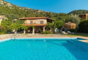 a villa with a swimming pool in front of a house at Stone house in Faralya in Fethiye