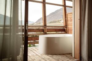 a bathroom with a tub in front of a window at Lake Spa Hotel SEELEITEN in Caldaro