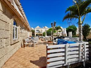 una valla blanca junto a un patio con mesas y sillas en Sweet Home Apartman, en San Miguel de Abona
