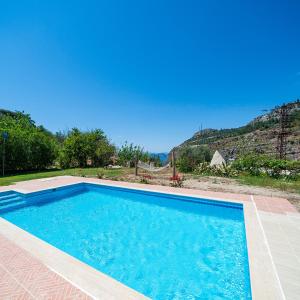 a large blue swimming pool with a mountain in the background at Stone house in Faralya in Fethiye