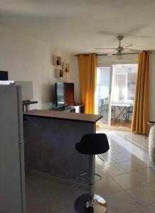 a living room with a kitchen with a counter and a chair at Studio cabine climatisé sur l'île des pêcheurs in Cap d'Agde +8 photos
