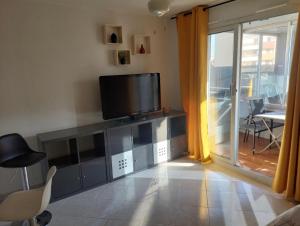 a living room with a television and a sliding glass door at Studio cabine climatisé sur l'île des pêcheurs in Cap d'Agde