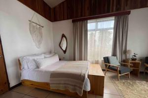 a bedroom with a bed and a chair and a window at Alas House, Monteverde with amazing sunset view! in Monteverde Costa Rica