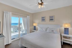 a white bedroom with a bed and a balcony at Crystal Tower 508 by Vacation Homes Collection in Gulf Shores