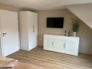 a living room with a white cabinet and a tv at Ferienhaus Mosel-Wohnen l in Bruttig-Fankel