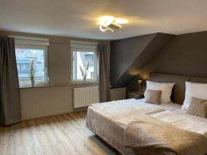 a bedroom with a large bed and two windows at Ferienhaus Mosel-Wohnen l in Bruttig-Fankel