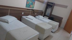 a room with three beds and a mirror at Prince Hotel in Ribeirão Preto