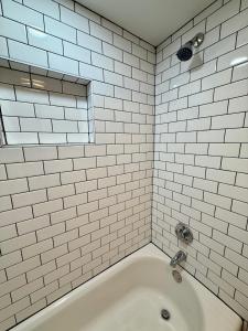 a white tiled bathroom with a bath tub at Aksarben Gem near UNO in Omaha