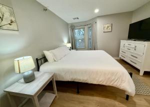 a bedroom with a large white bed and a table at Aksarben Gem near UNO in Omaha