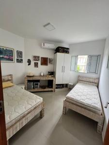 ein Wohnzimmer mit 2 Betten und eine Küche in der Unterkunft Casa de praia com piscina Barra Velha in Barra Velha