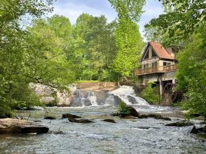 ein Haus auf einer Brücke über einen Fluss mit Wasserfall in der Unterkunft Lay Lodge at Falling Water Resort in Walhalla