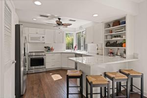 una cucina con armadi bianchi e un'isola cucina con sgabelli. di You Had Me at SSI - 107 Demere Retreat Lane a East End
