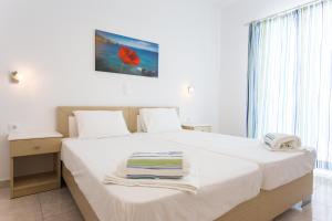 a bedroom with a white bed with towels on it at Theologos Beach in Antiparos