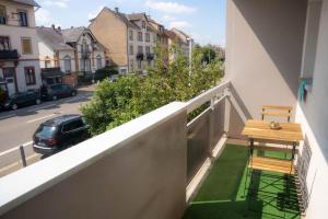 ein Balkon mit einem Holztisch und einer Bank an einer Straße in der Unterkunft Charmant 2 Pièces proche Hôpital de Hautepierre in Straßburg