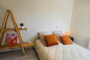 Bett mit orangefarbenen Kissen in einem Zimmer in der Unterkunft Charmant 2 Pièces proche Hôpital de Hautepierre in Straßburg