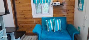 a blue couch in a room with a window at Sugar Cakes Tiny House in Governorʼs Harbour +3 photos