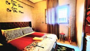 een slaapkamer met een bed met een opschrift op de muur bij Apprt Ennakhil 3 in El Jadida