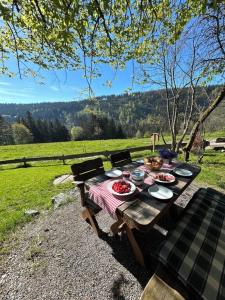Una mesa de picnic de madera con platos de comida encima. en Ferienhaus Bruno - Chalet mit 2 Schlafzimmern, en Feldberg