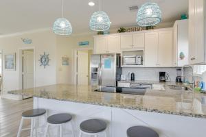 Una cocina con gabinetes blancos y taburetes de bar. en Walk to Beach Coastal Gem in Bolivar Peninsula!, en Bolivar Peninsula