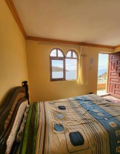 a bedroom with a bed and a window at Hostal Mirador del Sol in Comunidad Challapampa