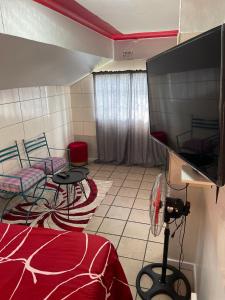 a room with a tv and two chairs and a table at Victoria Guest House in Alberton