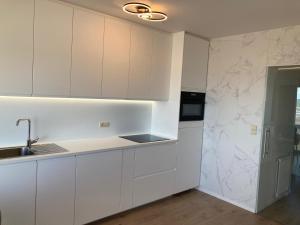 a kitchen with white cabinets and a sink at Zicht op Zee Koksijde in Koksijde