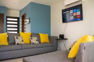 - un salon avec un canapé gris et des oreillers jaunes dans l'établissement Modern House 3 Bedrooms & Pool Acapulco, à Acapulco