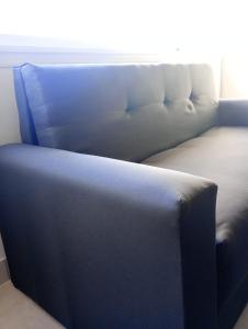 Un sofá azul situado en una habitación junto a una ventana en Apart Alsina V, en Junín