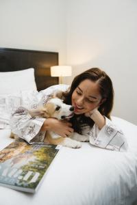 a woman laying on a bed with a dog at Kimpton Margot Sydney by IHG in Sydney