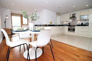 a kitchen with white chairs and a table with a dining room at Stylish City Apt, Balcony Near Stadium & Station in Cardiff