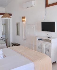 a white room with a bed and a flat screen tv at Restaurante & Pousada Gaivota in Santo André