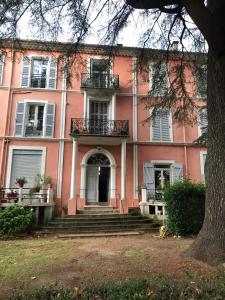 un bâtiment rose avec un escalier devant dans l'établissement Superbe T2 dans un parc arboré, à Lamalou-les-Bains 7 autres photos