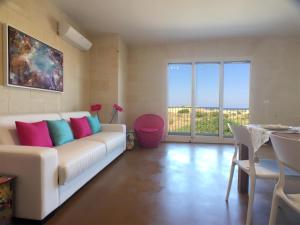 a living room with a white couch with colorful pillows at GozoWindmill Apartments in Qala