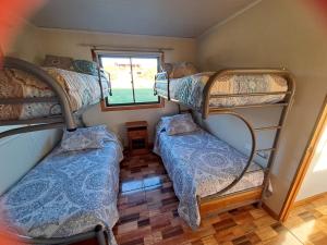 a room with three bunk beds and a window at Cabaña Nukutiare in Hanga Roa
